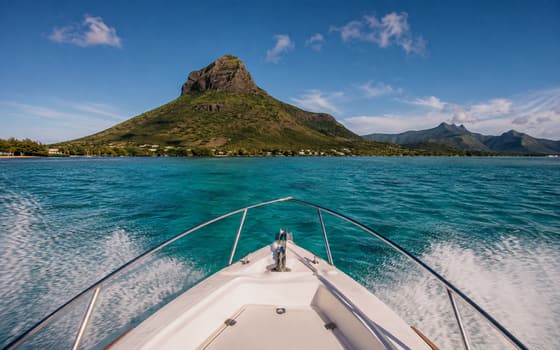 La proue du bateau fend le lagon vers une montagne verte